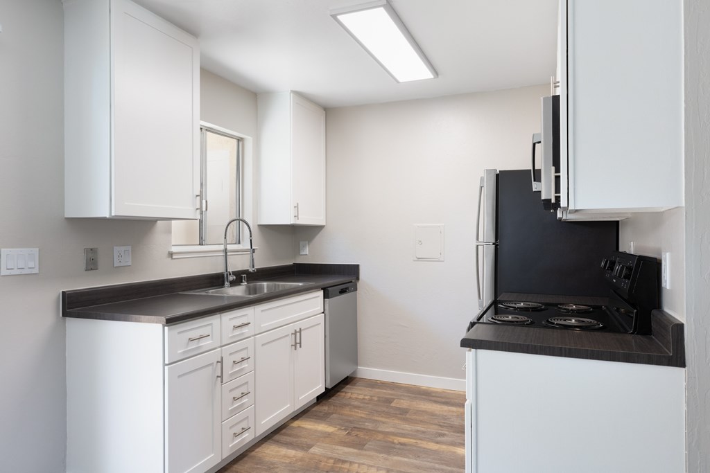 a kitchen with white cabinetry and black countertops